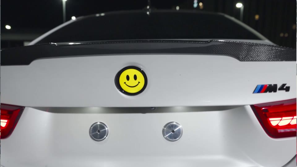 Digital rear badge displaying a custom graphic on a parked BMW